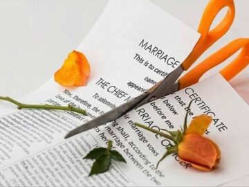 Marriage certificate being cut in half with orange handled scissors