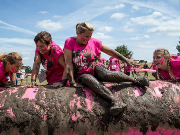 four women wearing pink t-shirts taking part in a pretty mudder 5k event